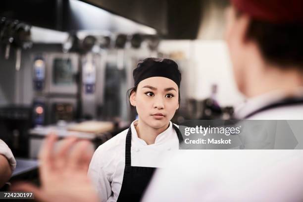 female chef student listening to teacher in cooking school - kochlehrling stock-fotos und bilder