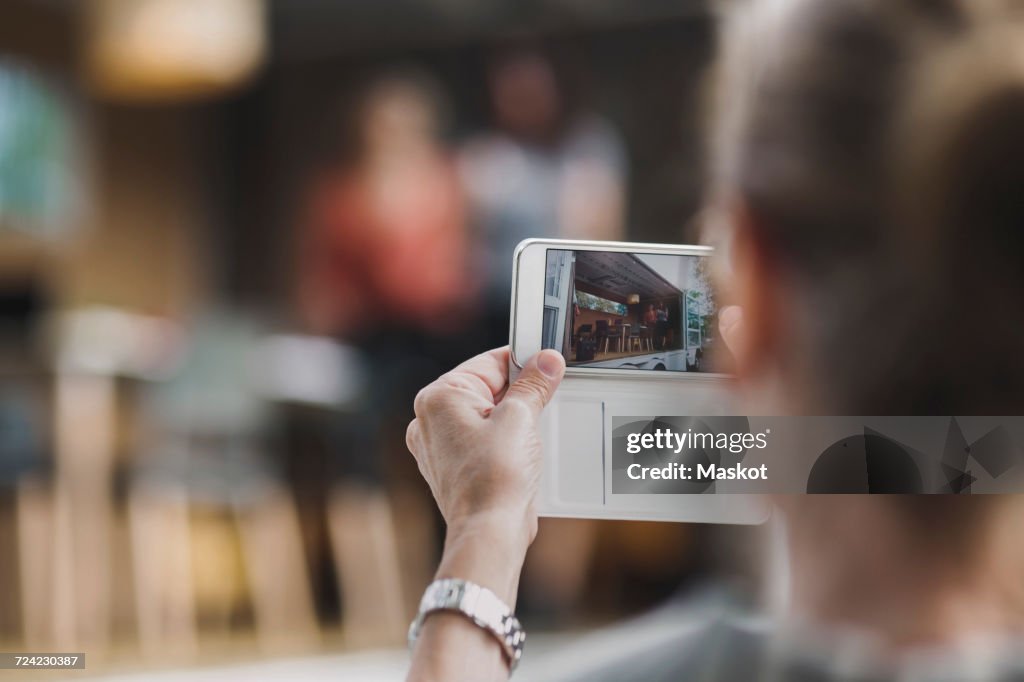 Rear view of businesswoman photographing colleagues through mobile phone in portable office truck