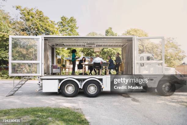 business colleagues discussing in portable office truck at park - old truck stock-fotos und bilder