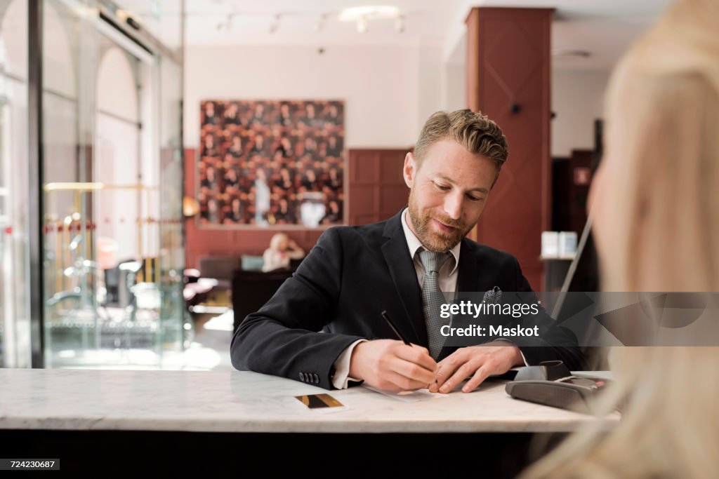 Mature businessman paying through credit card at hotel reception