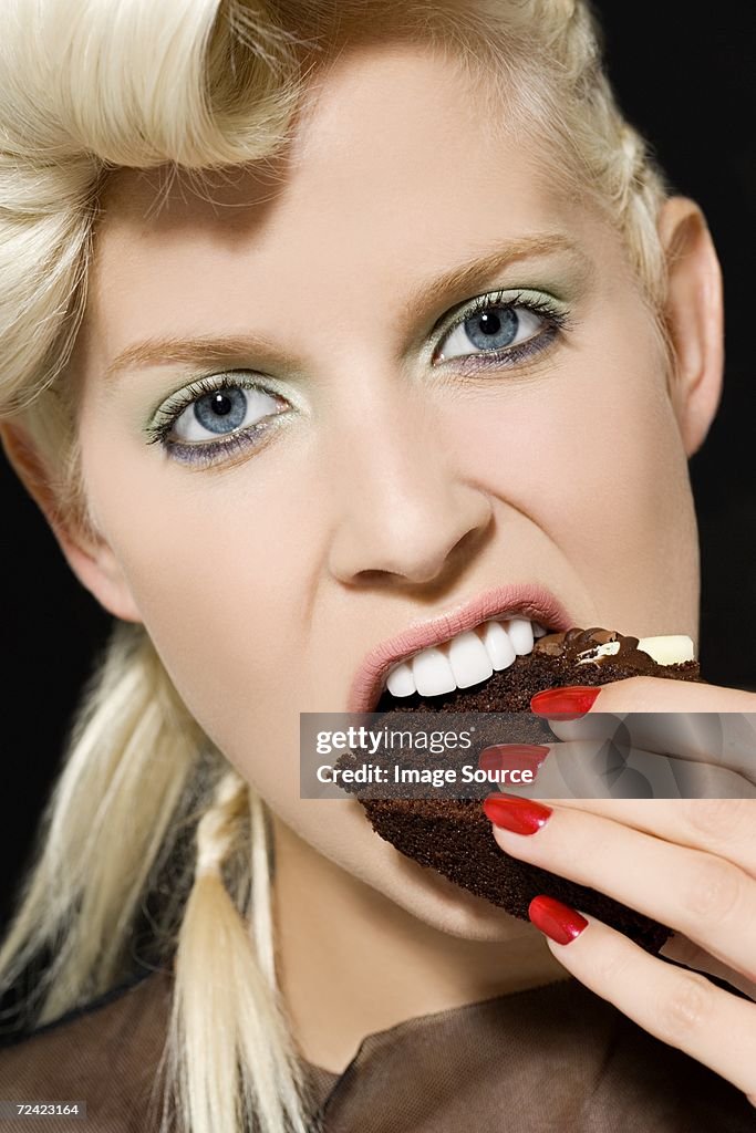 Woman biting a slice of cake