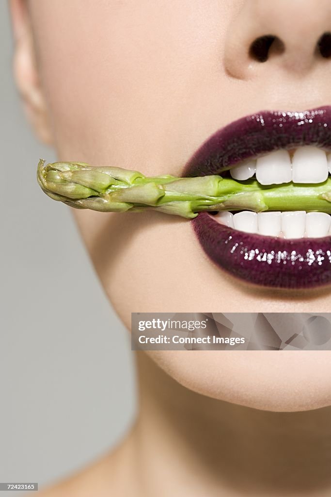 Woman with asparagus in her mouth