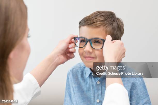 female optician putting glasses on boy - kids eyeglasses stock pictures, royalty-free photos & images