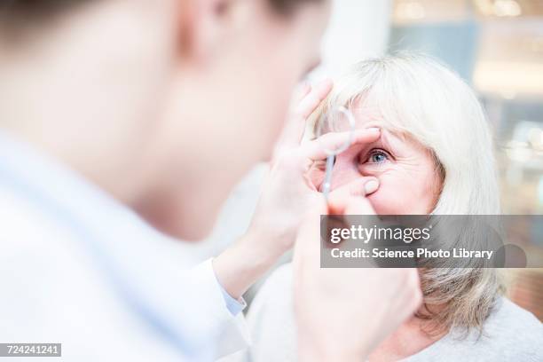 optometrist with magnifying glass - ophthalmologist stock pictures, royalty-free photos & images