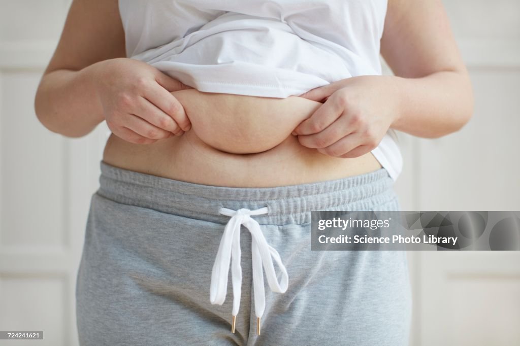 Woman holding folds of skin on tummy