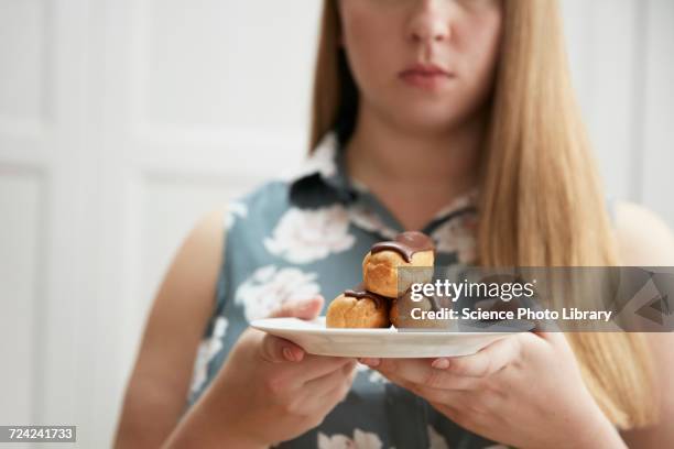 young woman holding plate of chocolate eclairs - eclair stockfoto's en -beelden