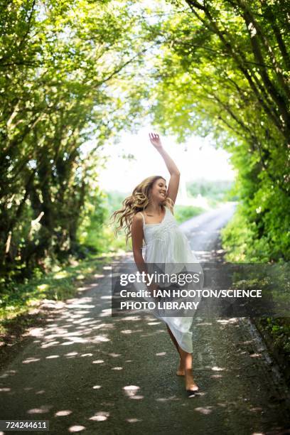 young woman dancing on country lane - single lane road stock-fotos und bilder