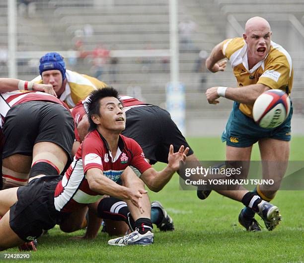 Japan's scrum-half Shota Goto passes the ball while Australian Prime Minister's XV flanker David Croft follows it during a friendly match at the...