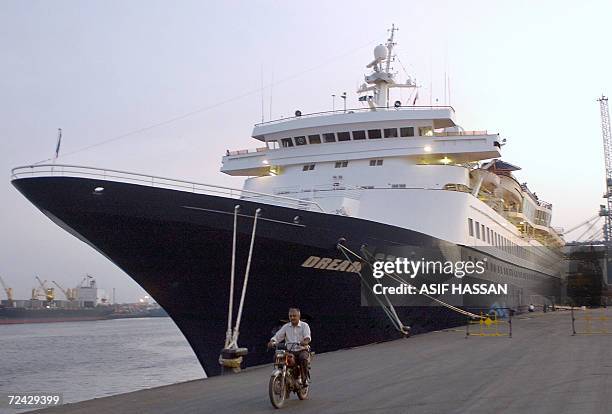 Pakistani man rides his motorbike past the Pakistan-Dubai luxury liner Dream Cruise at Karachi harbor, 07 November 2006. The Gulf Dream Cruise vessel...