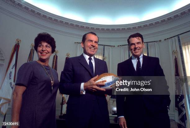 President Richard Nixon flanked by Rams football team owner George Allen and his wife; they have just given Nixon a special Pro Bowl football.
