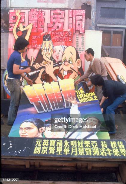 Workers change movie billboard.