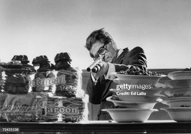 Head of nutrition advocacy group Heartsavers Phillip Sokolof holding up gun & taking aim at stacks of cookies & cereals containing palm & coconut oil...