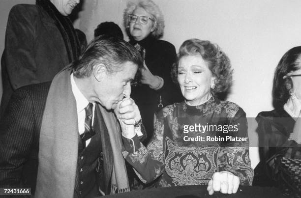 Actress Myrna Loy getting hand kissed by Roddy McDowall at tribute thrown for her.