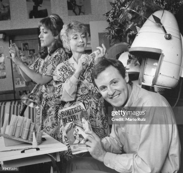 Playwright, Robert Harling posing in beauty parlor chair on the stage set with cast members, Constance Shulman & Rosemary Prinz dressed for their...