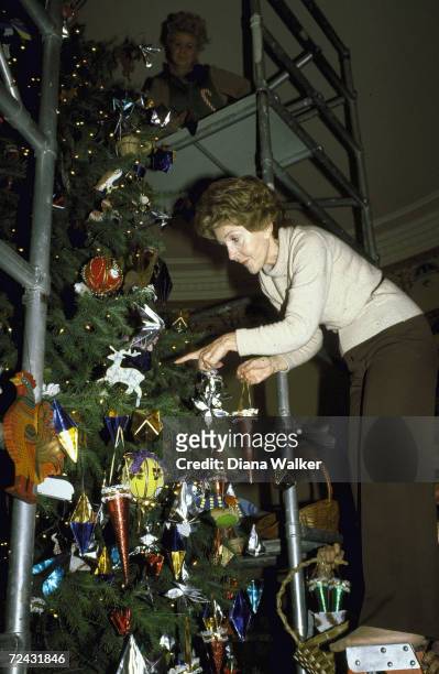 First Lady Nancy Reagan trimming Christmas tree.