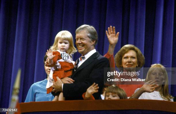 President Jimmy Carter holding his granddaughter Sarah Rosemary Carter, being flanked by First Lady Rosalynn Carter and daughter Amy, at the...