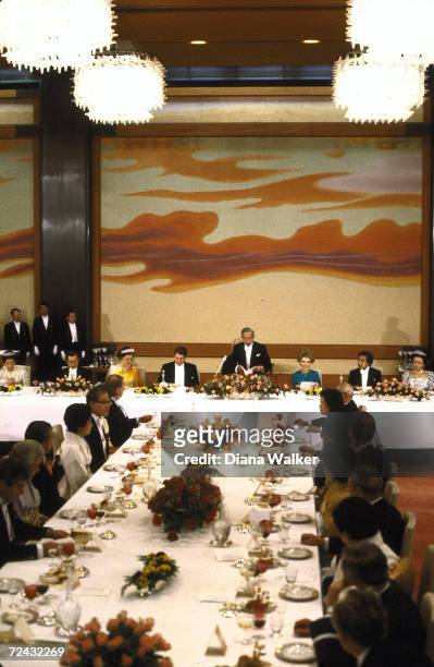Japanese emperor Hirohito standing to address guests, incl. President Ronald Reagan and first lady Nancy Reagan at white tie banquet at Imperial...