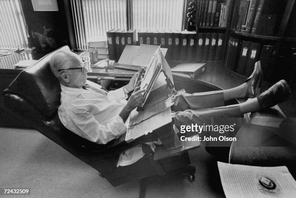 Endocrinologist Dr. Hans Selye with feet up on desk dictating into microphone at lap worktable of his own design in his office at University of...