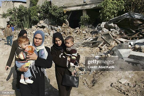 Palestinian women carry their babies as they walk through the rubble of homes, destroyed by Israeli bulldozers, on November 7 in Beit Hanoun, in the...