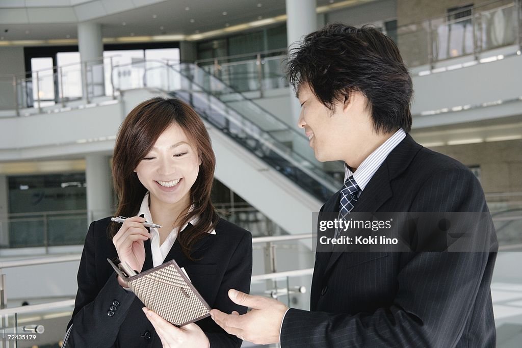 A young woman and a mid adult man talking in lobby