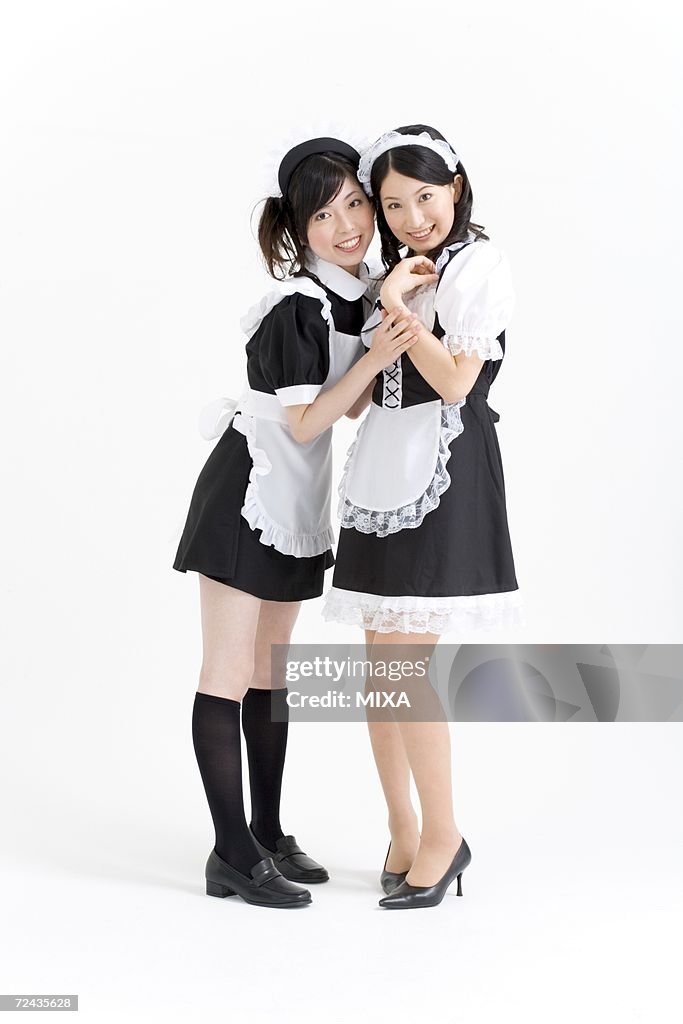 Two young women in French maid outfit smiling