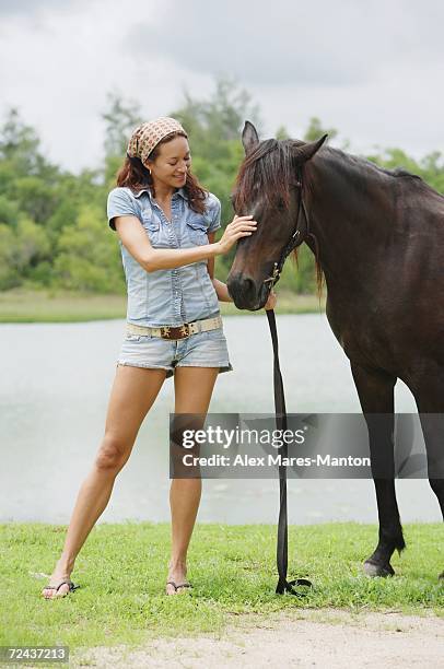 woman petting horse - カットオフジーンズ ストックフォトと画像