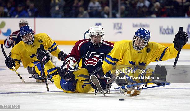 Patrick Byrne of the USA runs over Goran Karlsson of Sweden while teammate Mikael Axtelius of Sweden goes for the puck in Men's Ice Sledge Hockey...