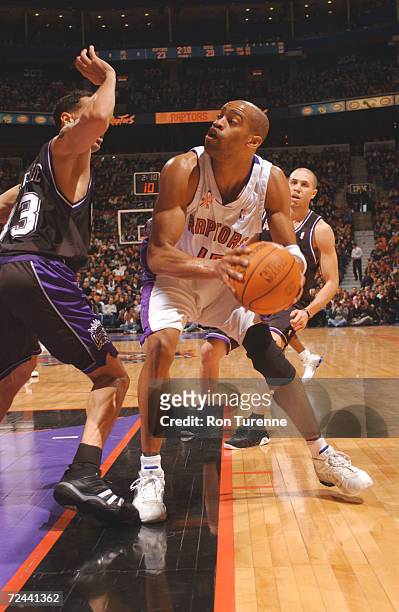 Vince Carter #!5 of the Toronto Raptors looks for the open man along the baseline as he is guarded by his former teammate Doug Christie of the...