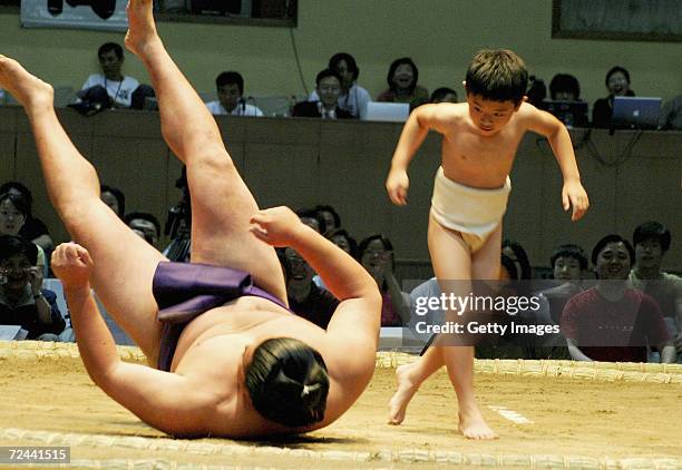 Little boy watches his oppponent, a professional sumo wrestler, fall after a "fight" during a pre- competition ceremony, on June 6 in Beijing, China....
