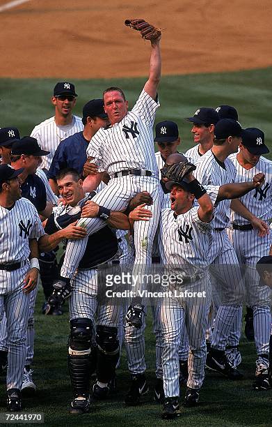 David Cone of the New York Yankees celebrates as his teammates lift him after winning the game against the Montreal Expos at Yankee Stadium in Bronx,...