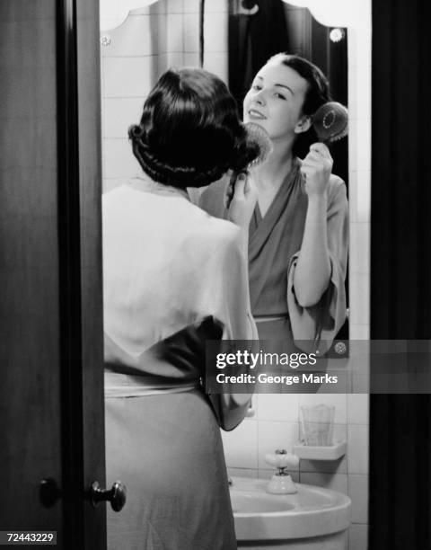 1950s: Portrait of woman brushing hair.