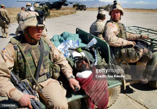 Army soldiers from the 101st Airborne transport an injured man who was taken prisoner during Operation Anaconda March 12, 2002 in the Shah-e-Kot...