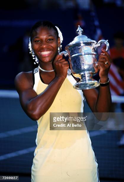 Serena Williams of the USA smiles and poses with her trophy after the match between Martina Hingis of Switzerland in the US Open day 13 at the USTA...