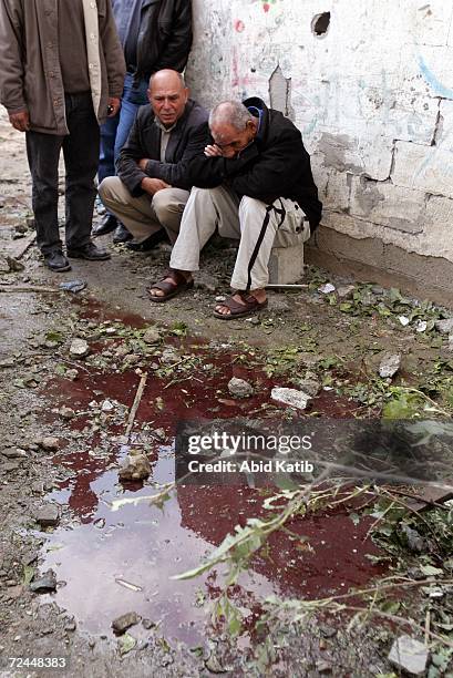 Palestinians mourn next to water stained with blood as it covers a street after Israeli tanks fired on homes on November 8, 2006 in Beit Hanoun in...