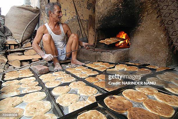 Indian baker Jai Krishan makes traditional Punjabi bread known as Kulcha, in his tandoor , 08 November 2006 in Amritsar, in India's northwestern...