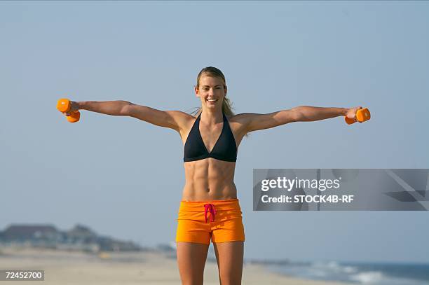 young blond woman training with tiny barbells at the beach - bauchmuskel stock-fotos und bilder