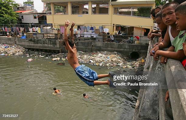 Filipino boy jumps into a polluted canal in the slums on July 19, 2005 in Manila, Philippines. Extreme poverty is commonplace in Manila where...