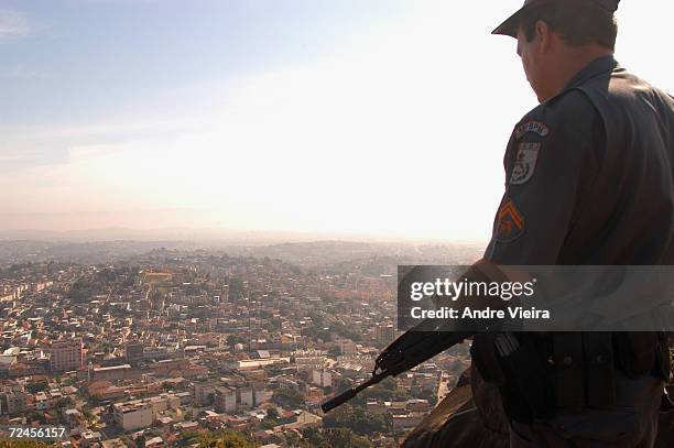 Heavily armed policeman provides security for construction workers at a cave site used by drug dealers to incinerate their victims in a bush area...