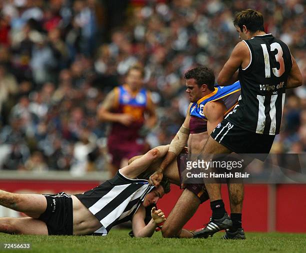 Ashley McGrath for Brisbane wrestles with Heath Scotland and Richard Cole for Collingwood during the AFL Grand Final between the Collingwood Magpies...