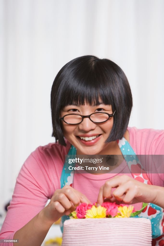 Young Asian woman putting flowers on cake