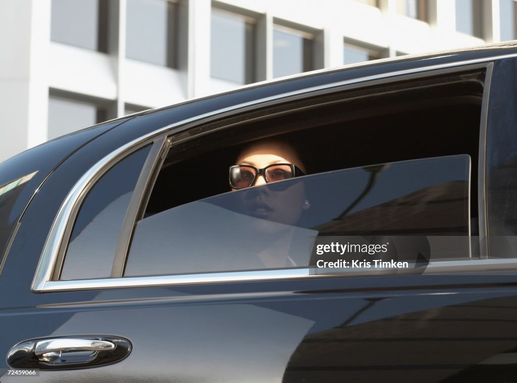 Asian woman in limousine with window part of the way down