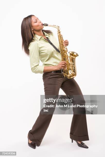 studio shot of african woman playing saxophone - saxophone stock-fotos und bilder