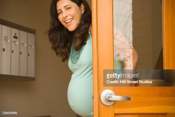 pregnant hispanic woman in doorway smiling - answering stock pictures, royalty-free photos & images