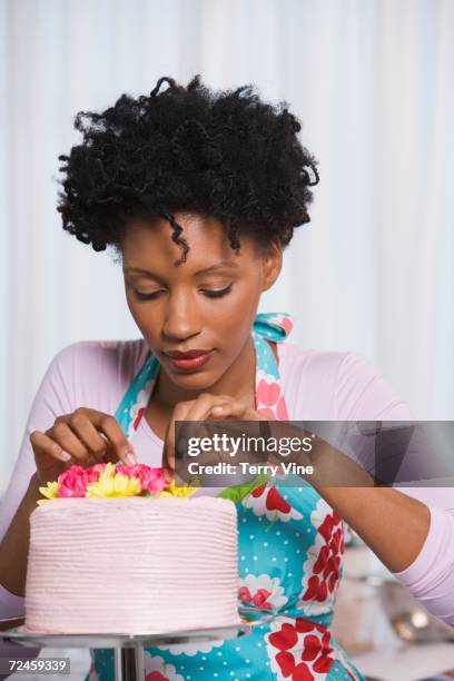 young african woman putting flowers on cake - decorating a cake fotografías e imágenes de stock