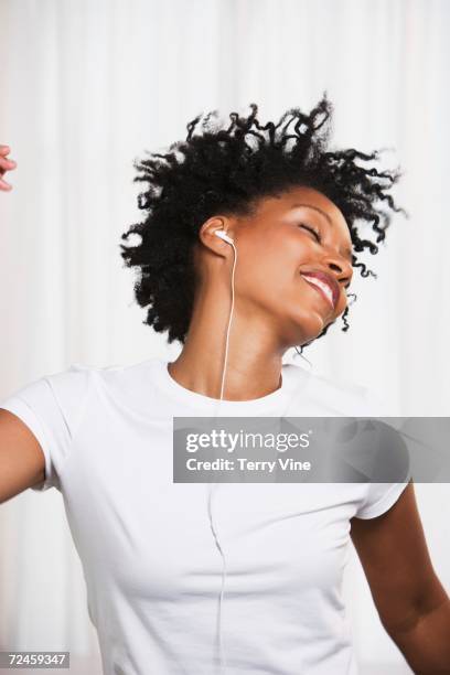 close up of young african woman dancing to music on ear buds - ear close up women stock-fotos und bilder