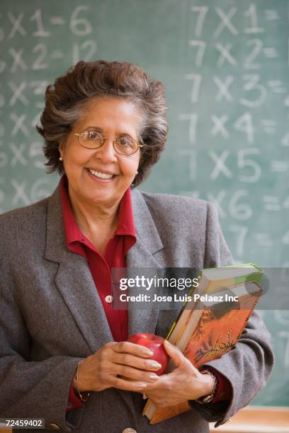 senior hispanic female teacher in front of blackboard - teacher in front of class stock pictures, royalty-free photos & images