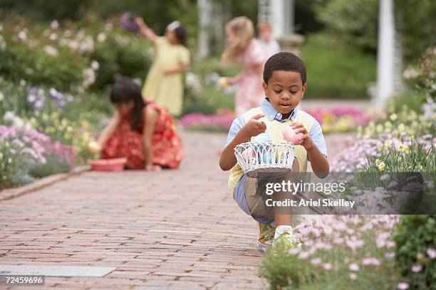 children gathering easter eggs in garden - african easter stock pictures, royalty-free photos & images