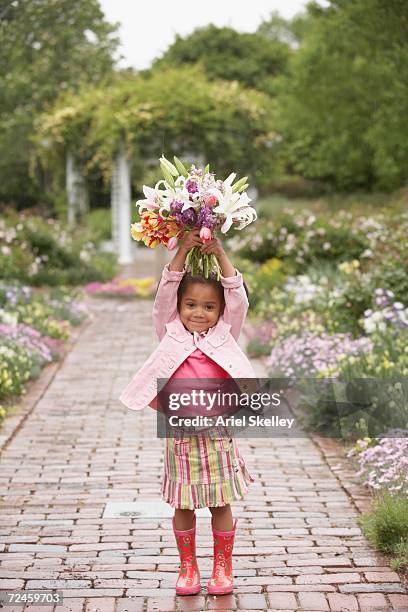 Young African girl holding flowers in garden