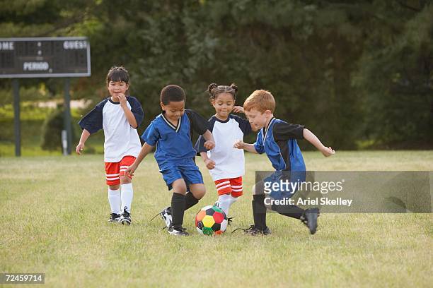 children playing soccer outdoors - jugador futbol fotografías e imágenes de stock