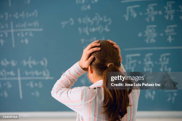 girl with hands on head looking at blackboard - teenager headache stock pictures, royalty-free photos & images